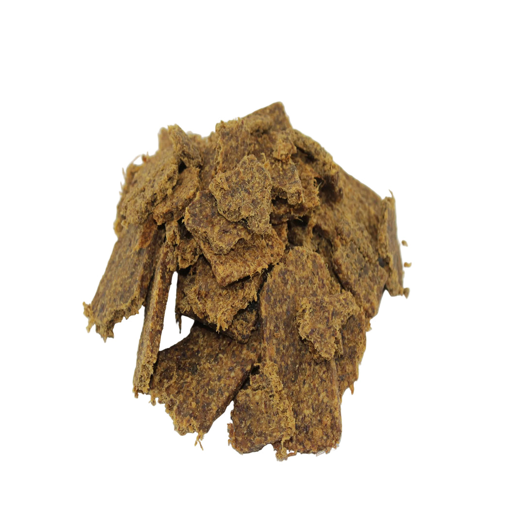 A pile of textured, irregular brown dried beef & green lipped mussel soft chips on a plain white background.