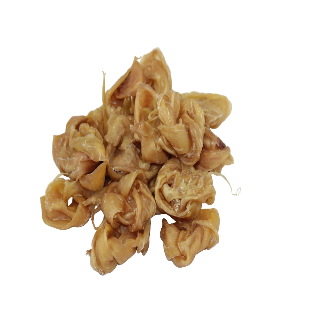 Curled-up veal tendon chews dog treats, in a golden-brown color, set against a plain white background.