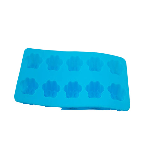 A bright blue silicone mold tray with ten dog paw shaped cavities, photographed on a plain white surface.